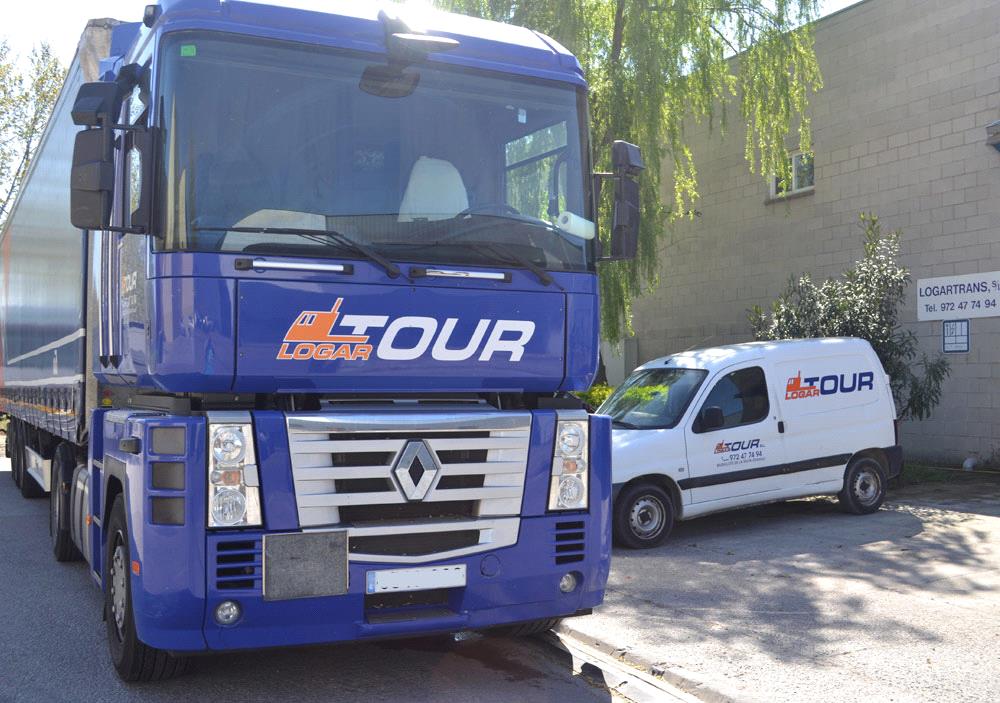 Camión furgoneta de asistencia de Logartour frente a sus antiguas oficinas, reflejando los años de experiencia y trayectoria de la empresa en el transporte.